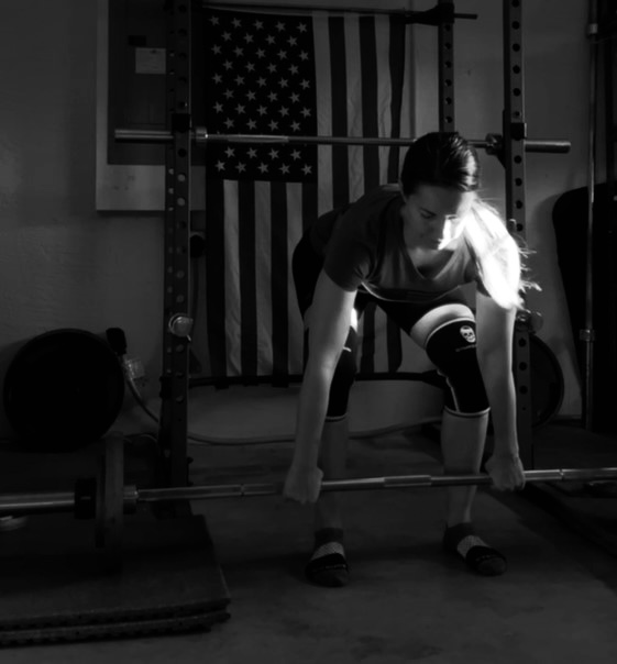 Lifter in squat rack preparing for a lift with American flag in background