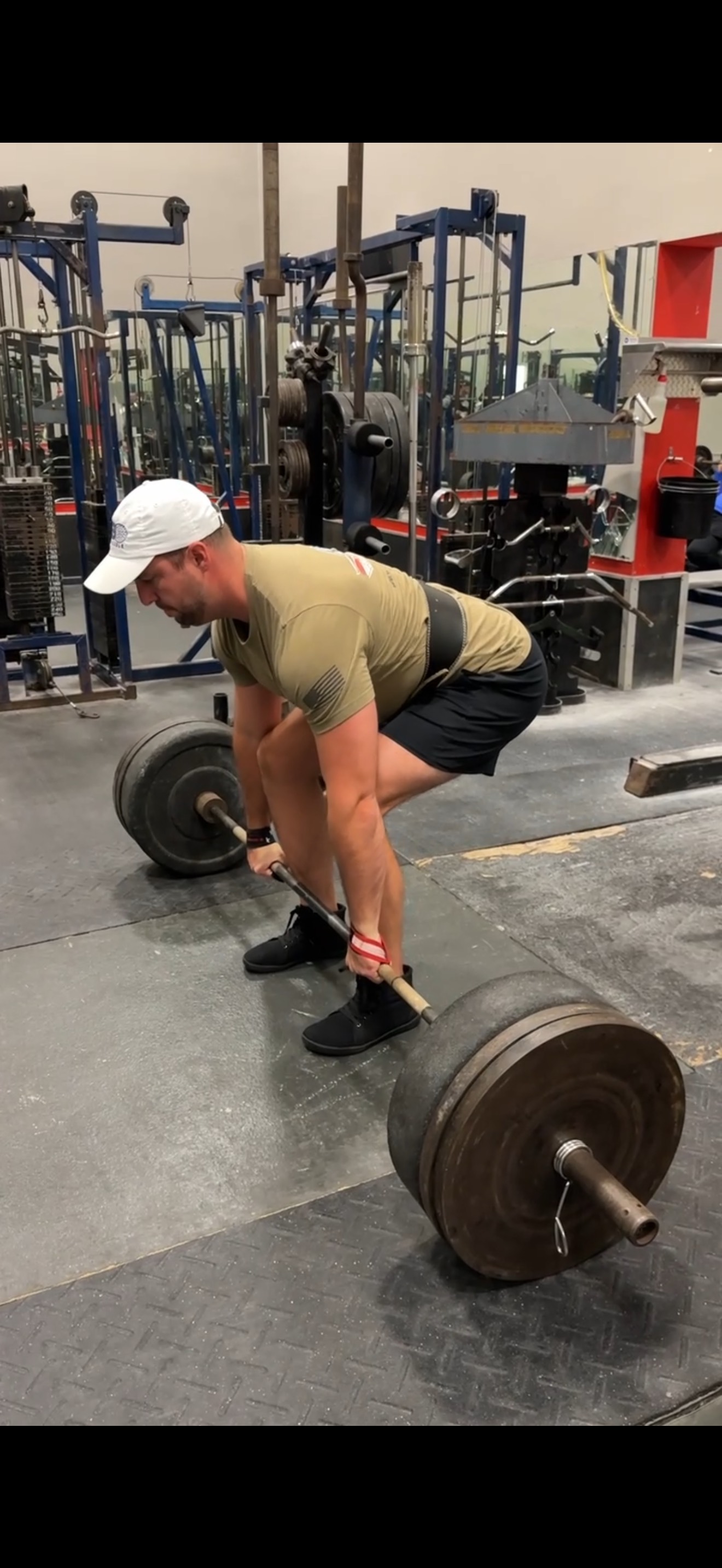 Athlete preparing for heavy deadlift with loaded barbell in commercial gym